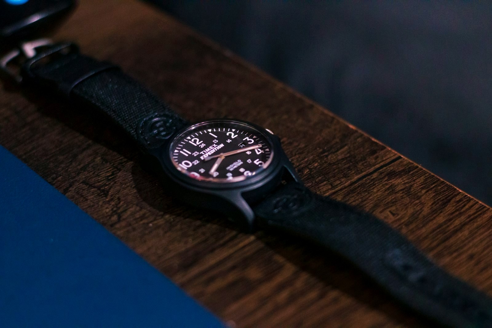 A black field watch on a wood table, the tactical register in one frame