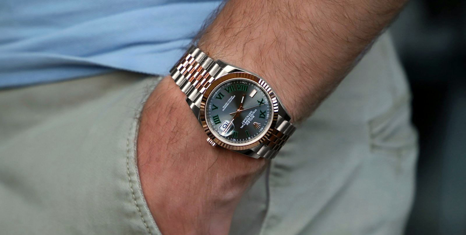 A steel watch on a wrist sliding into a trouser pocket