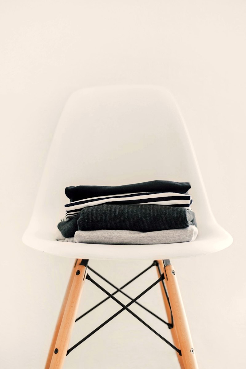 Neatly folded garments in cream tones on a white chair
