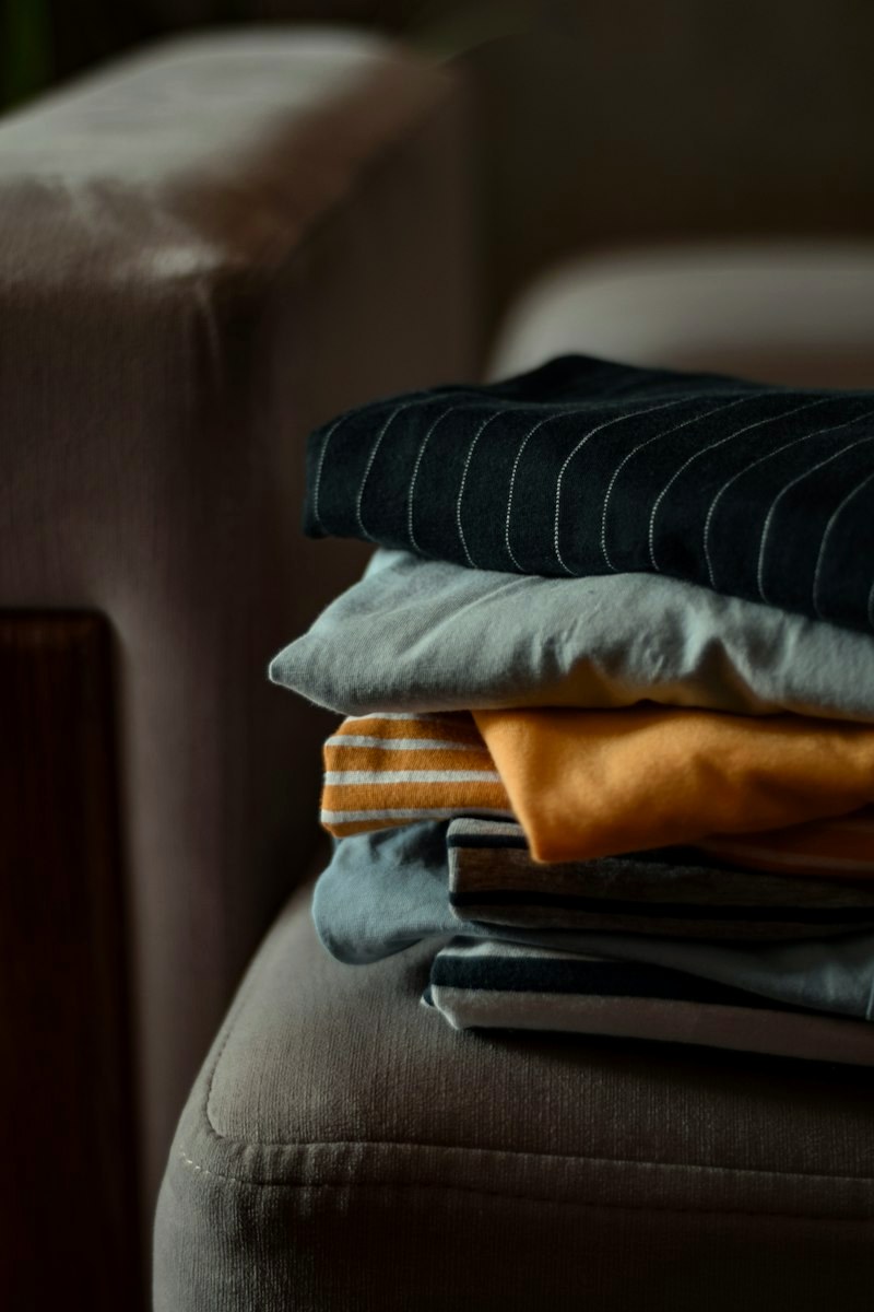 Stack of folded casual garments on a sofa