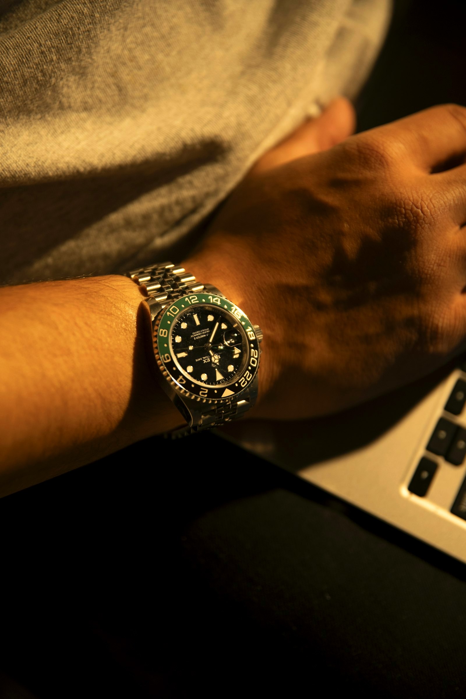 A diver's watch on a wrist resting at a laptop, the everyday desk carry