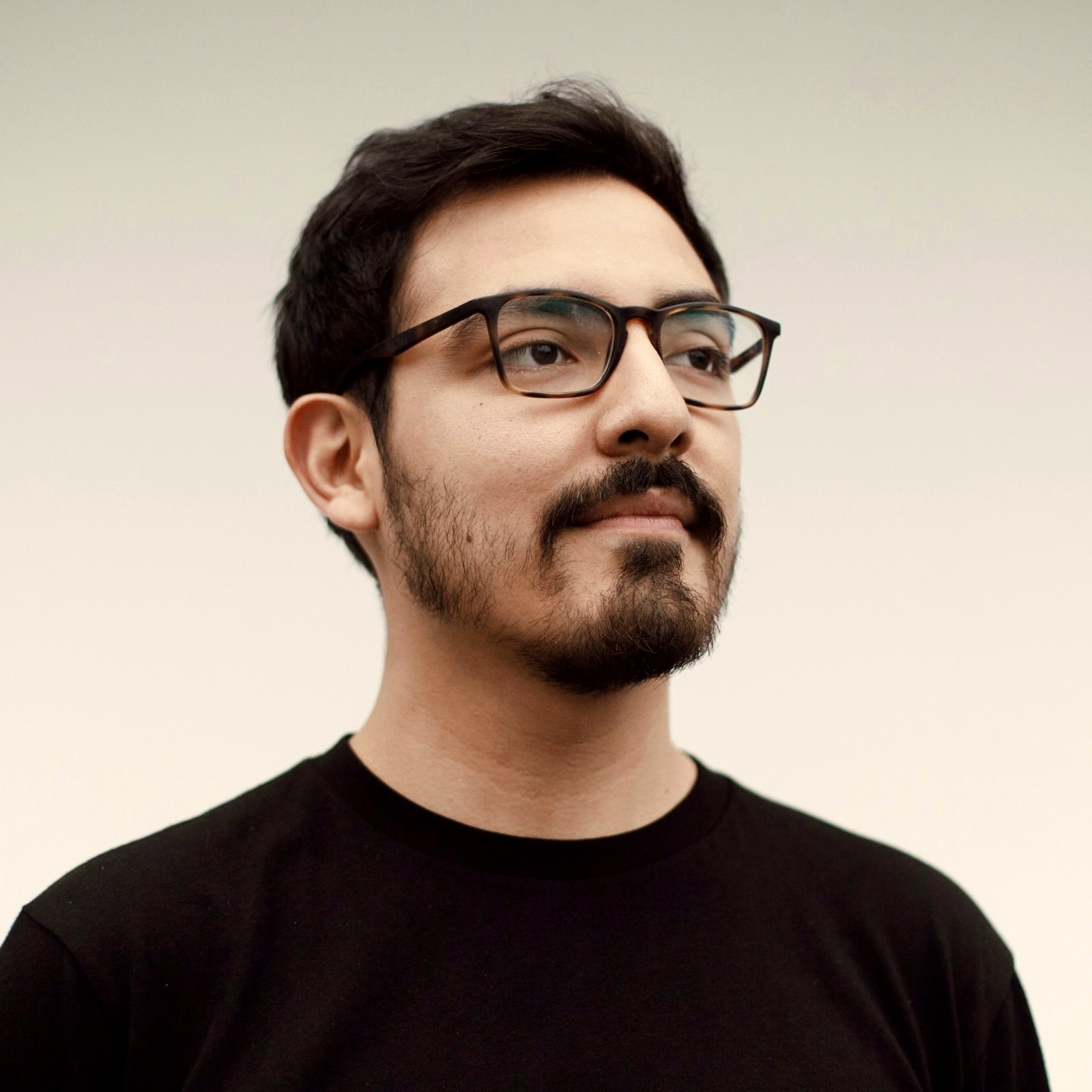Young man with a short beard wearing rectangular tortoiseshell frames with a strong straight top line