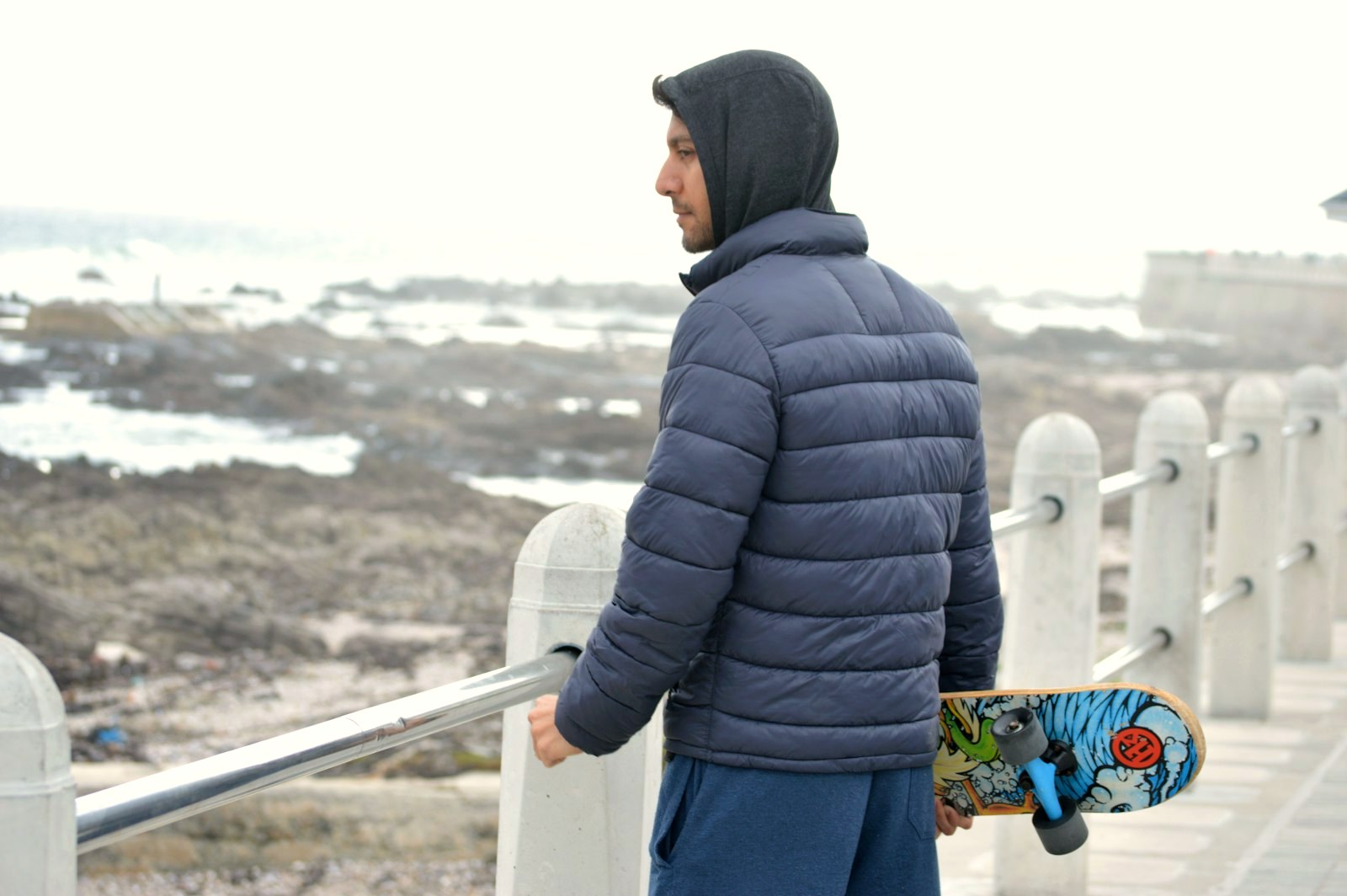 Man in a navy puffer jacket at the coast