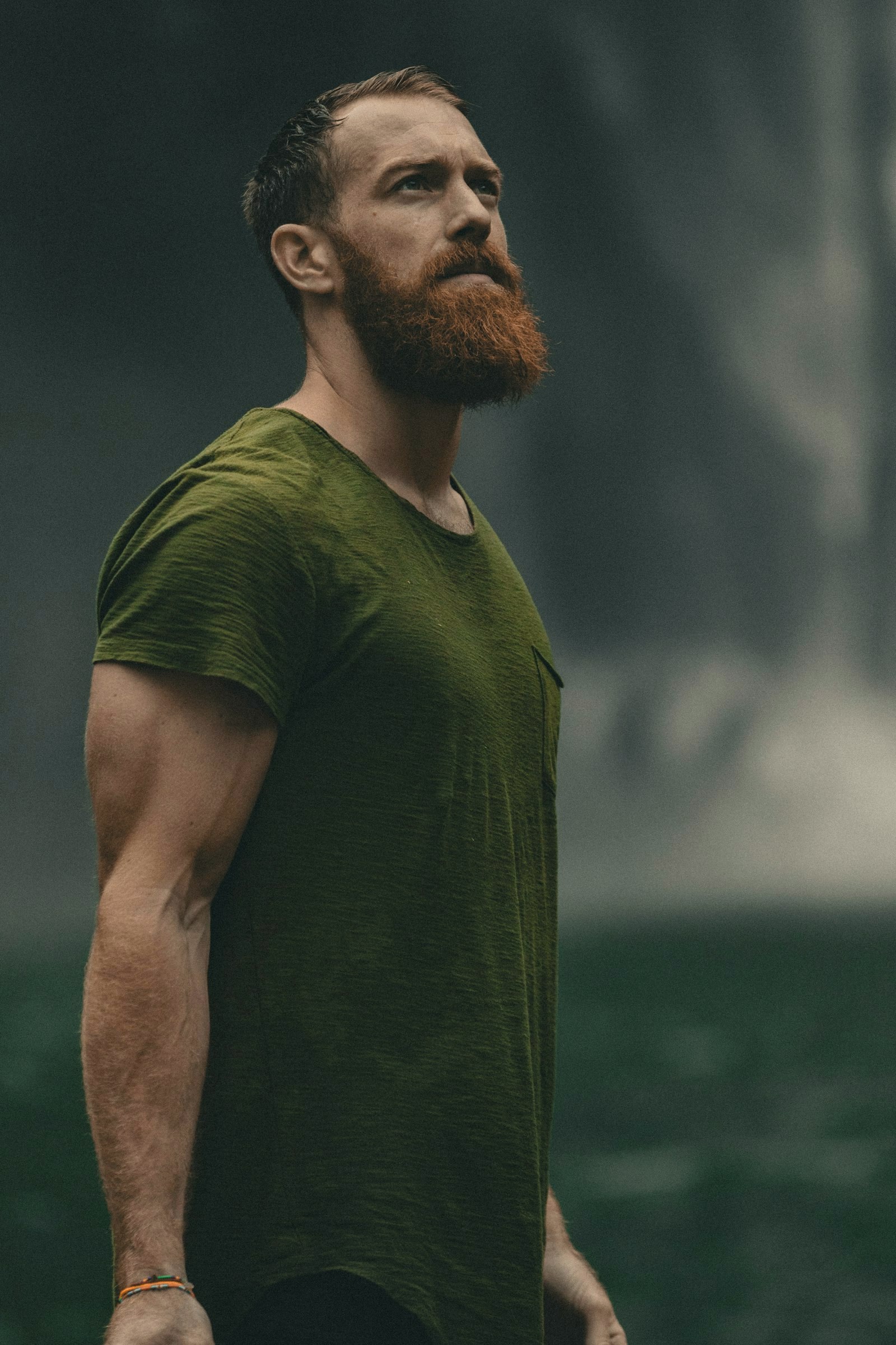 Man with a red beard and full natural brows in a green t-shirt