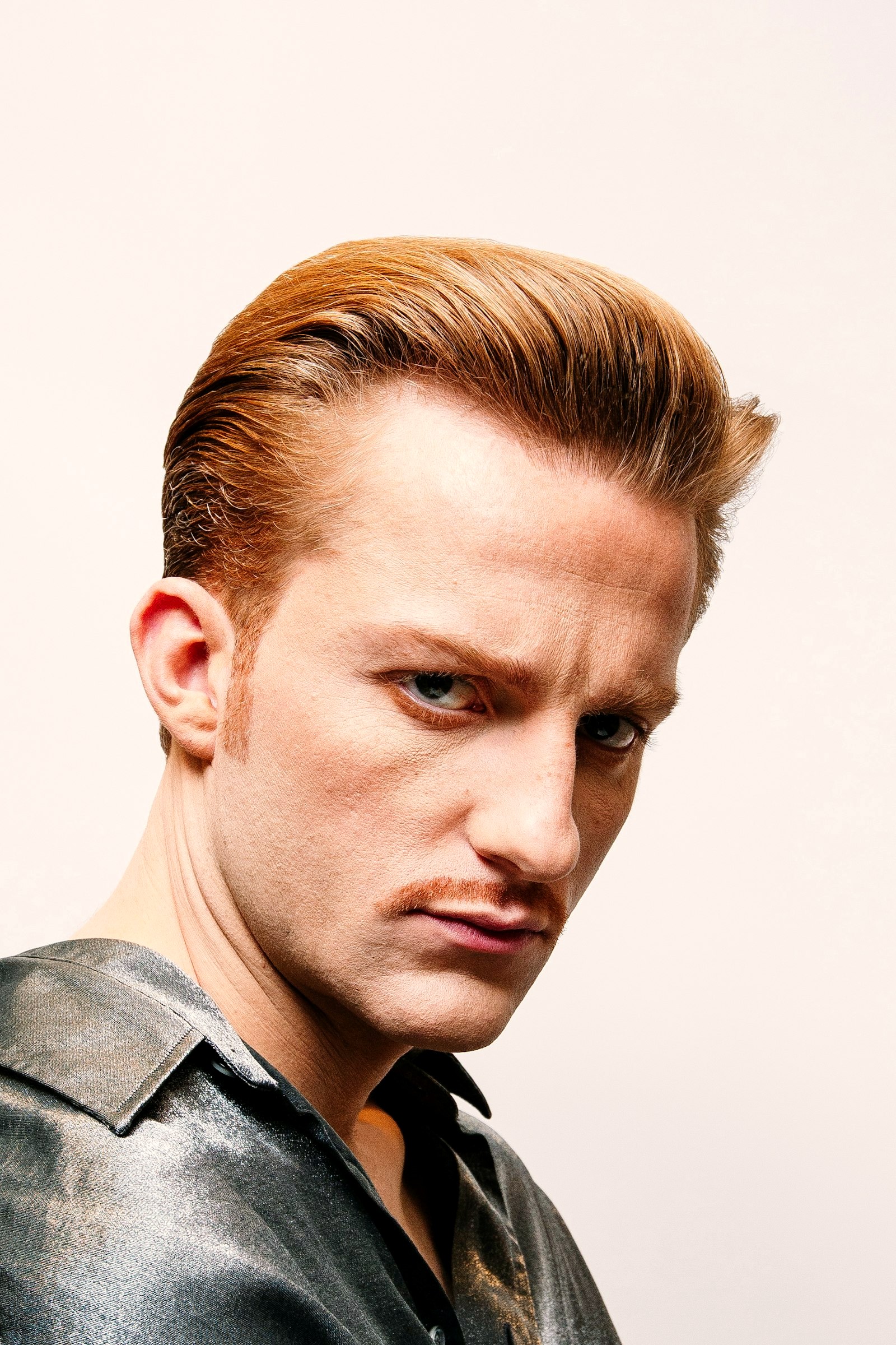 A slicked pompadour in studio light, hair combed back and held in place