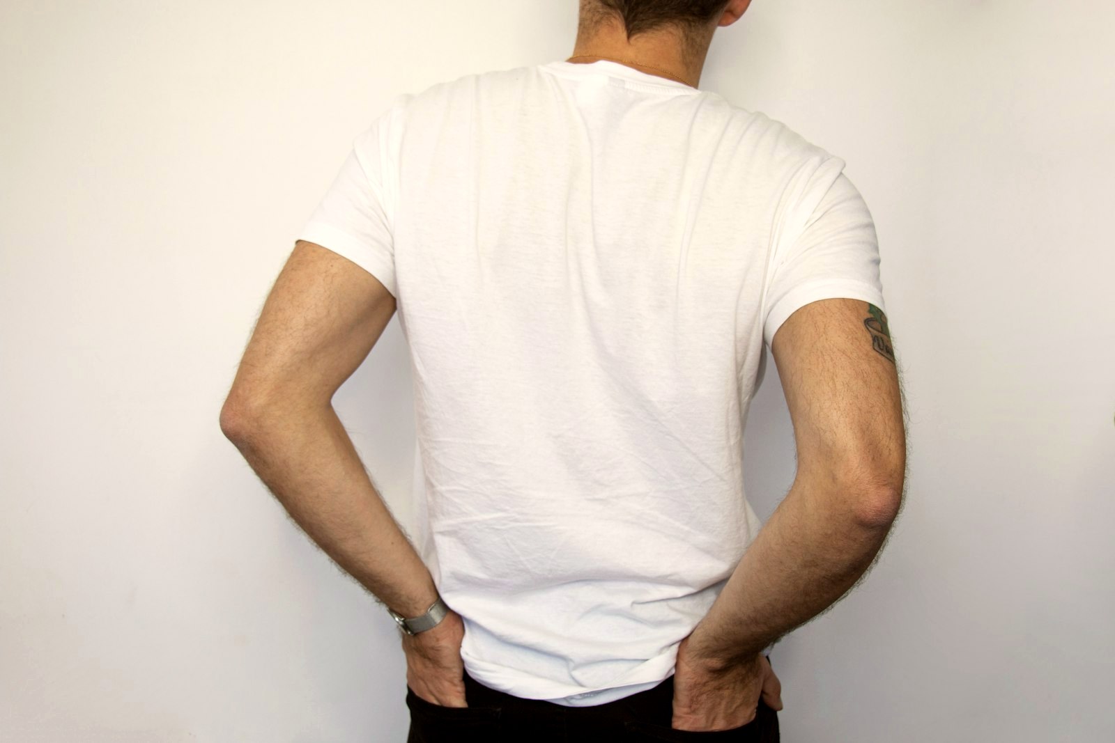 Back view of a man in a plain white t-shirt, showing the fall of the cloth
