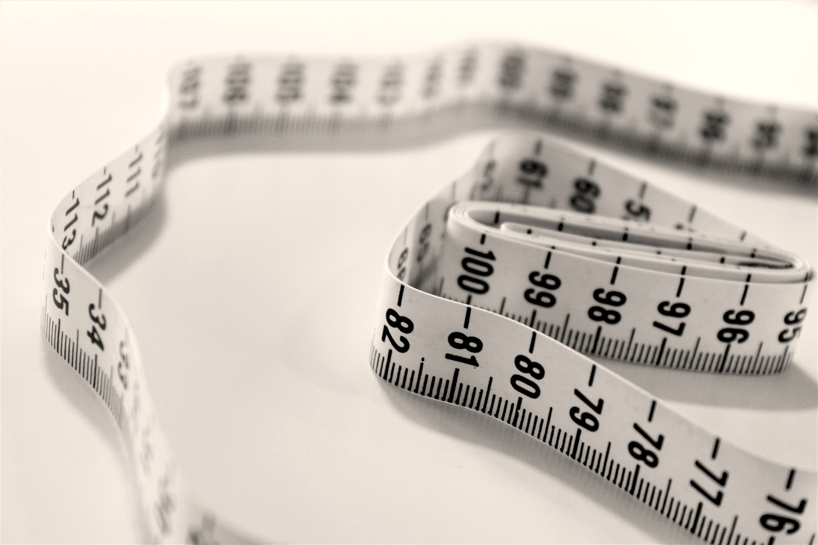 A white measuring tape coiled on a white ground