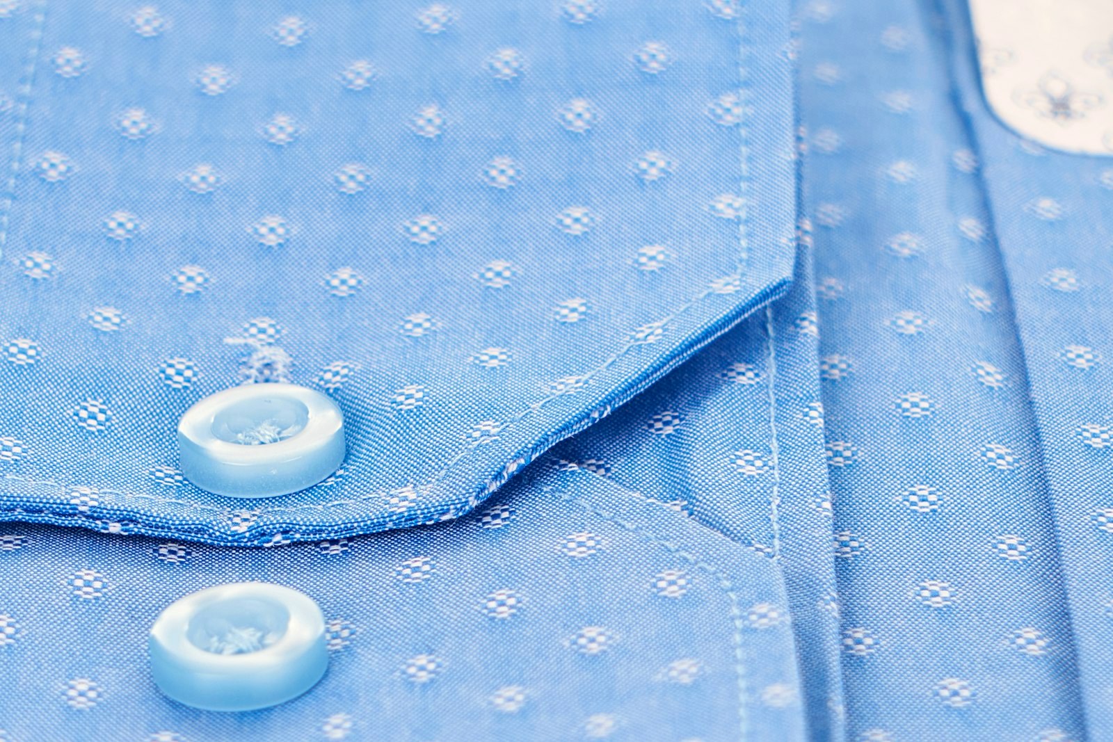Close detail of a shirt collar point, cuff and buttons showing the weave