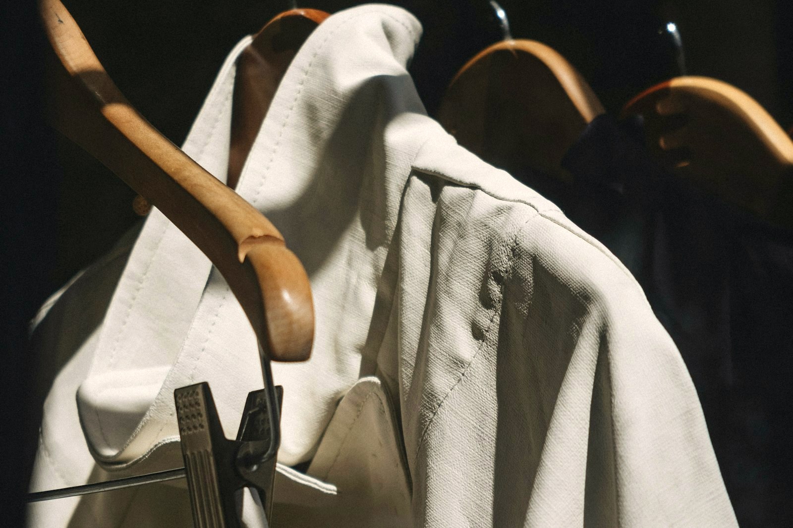 White shirts hanging on a rail in low light