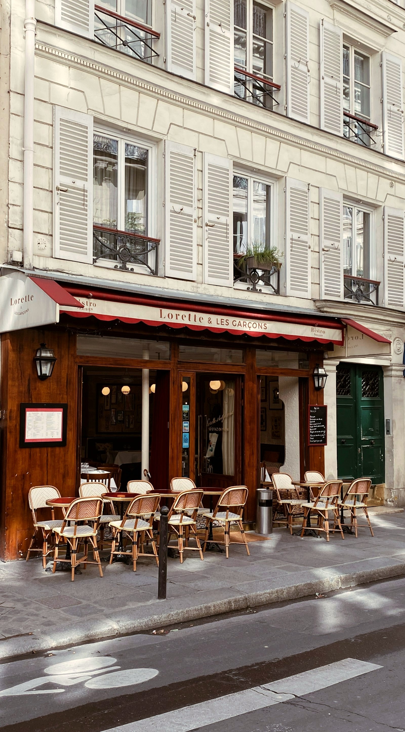 A café storefront under a red awning, the other rain shelter, in the retail register this coat is priced in