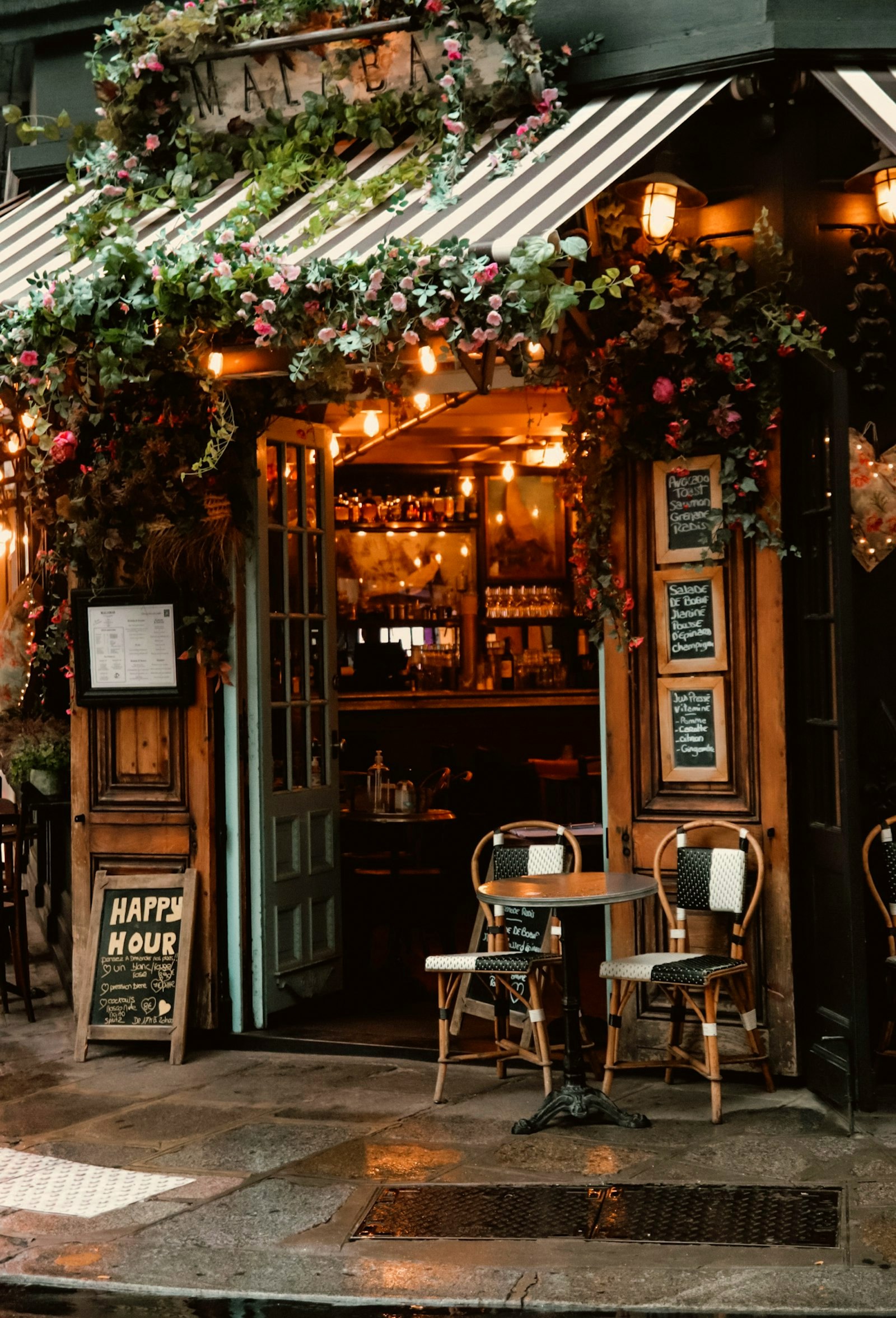 The ivy-covered entrance of a café in the evening, tables set outside, the destination the apps on this page exist to reach