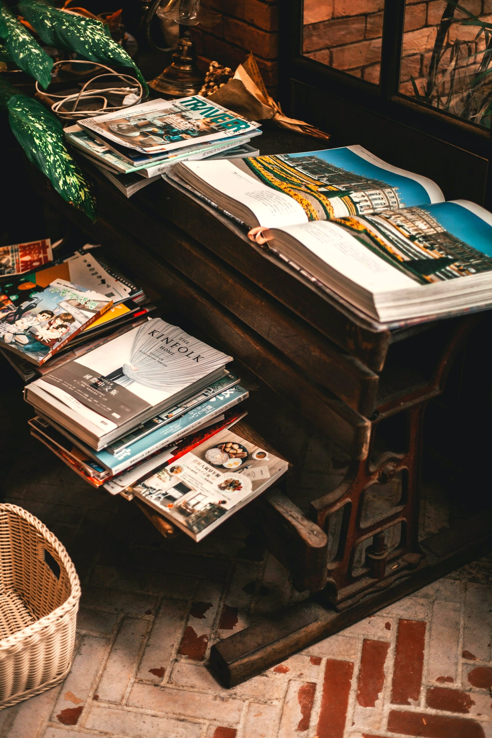 Magazines and an open photo book stacked on an antique press table in a Paris cafe