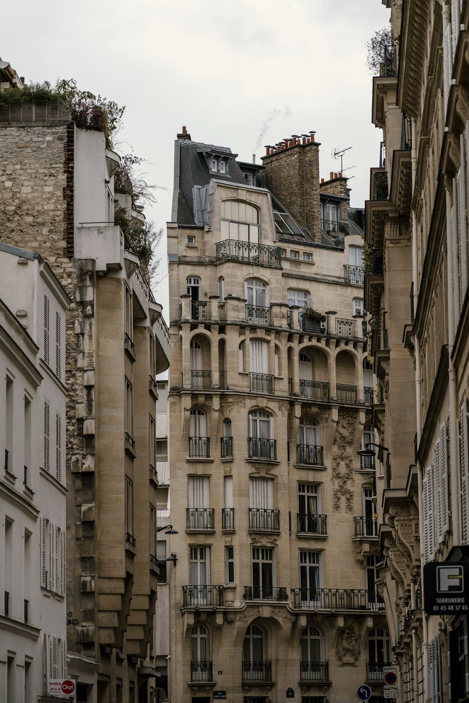 Tall Haussmann facades closing over a narrow Paris street