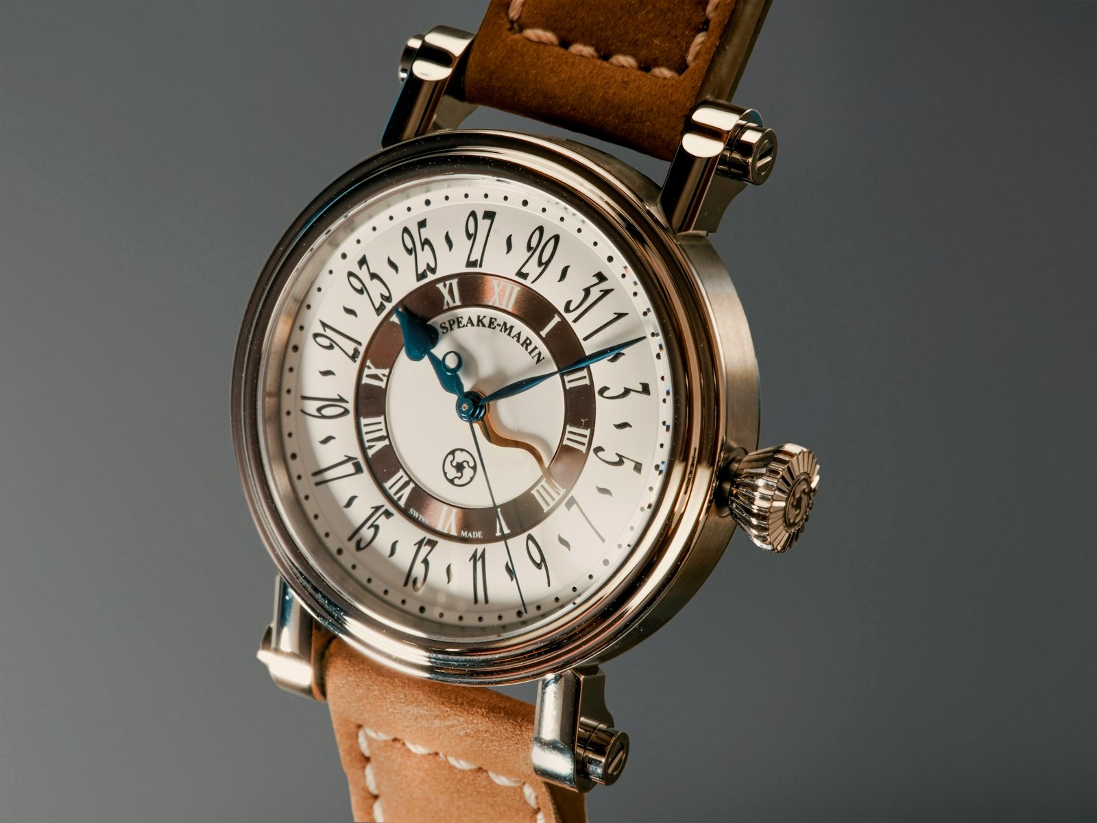 A white-dial dress watch on a tan suede strap in a studio frame