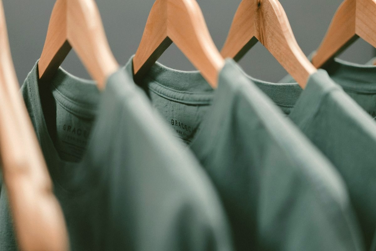Sage-green shirts hanging on wooden hangers