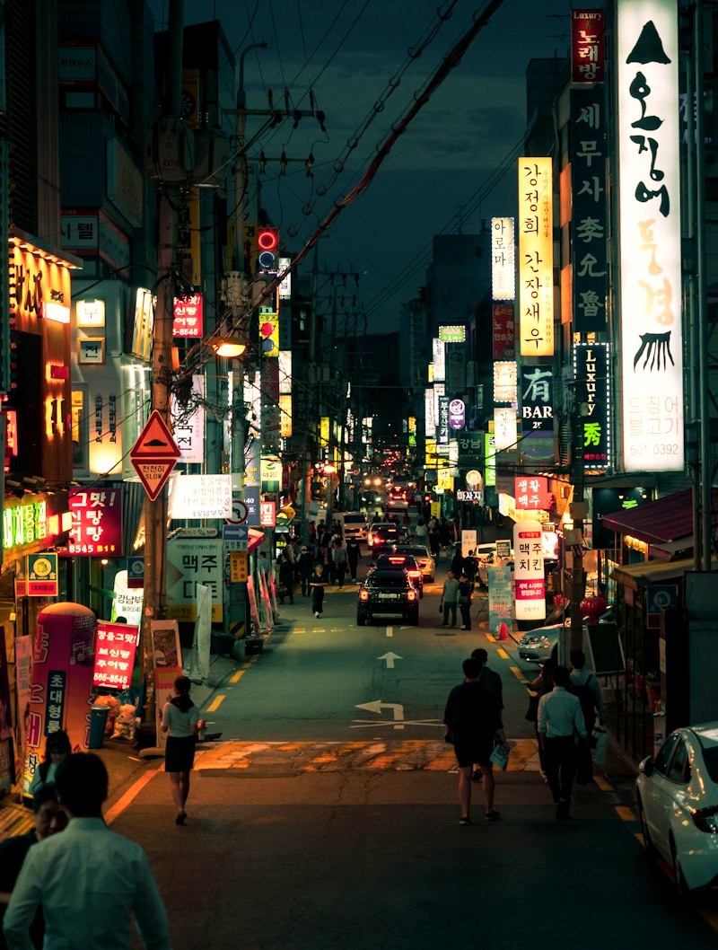 Neon signs stacked over a night street, volume as a design language, the register this frame is priced for