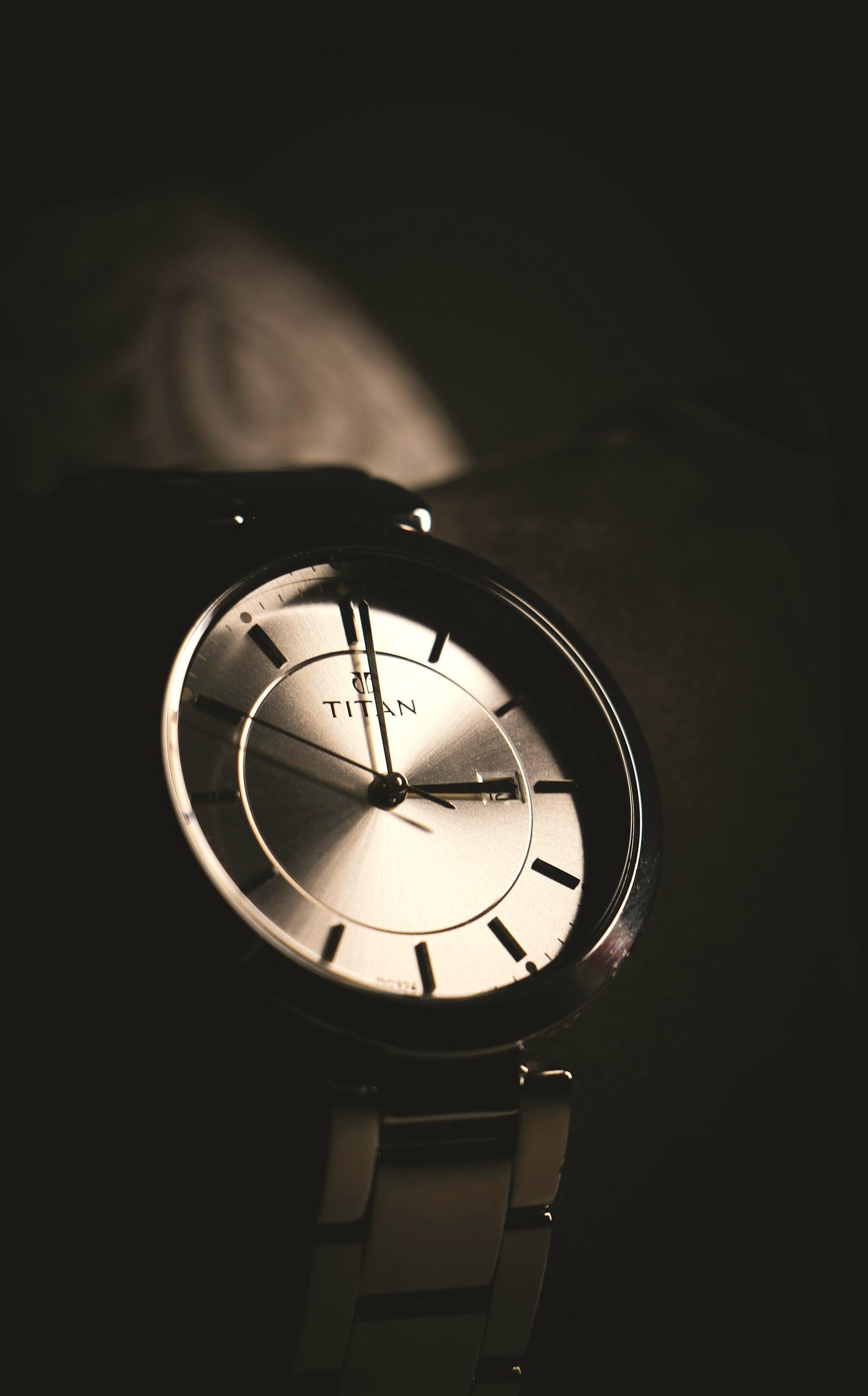 A slim silver minimal dial on a steel bracelet at macro range in low light