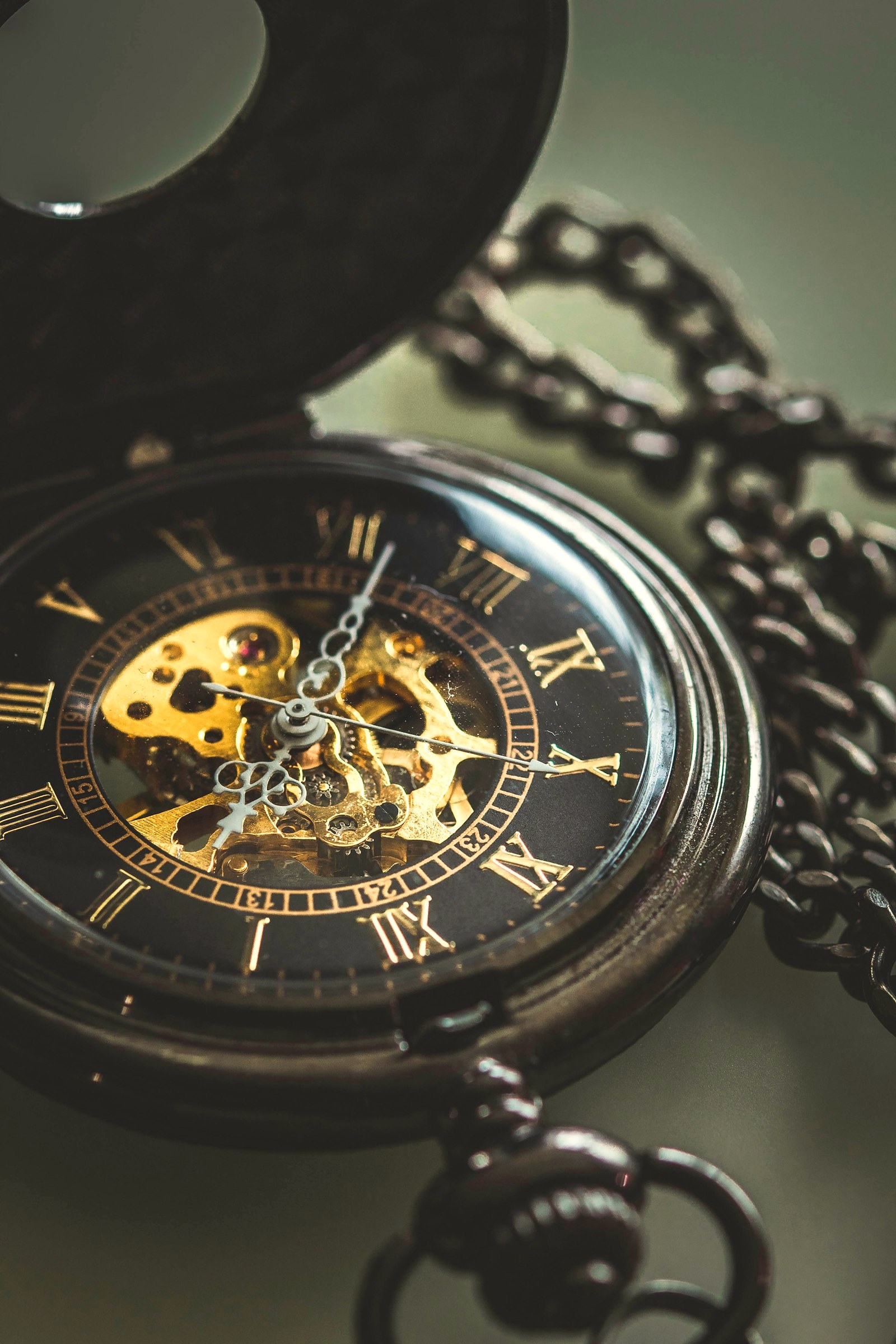 An open skeleton pocket watch, its mechanism visible, on its chain