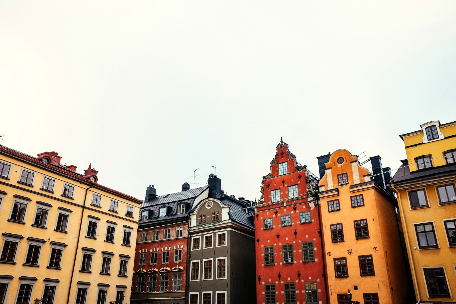Old town facades in Stockholm in ochre, rust red and cream under a pale sky