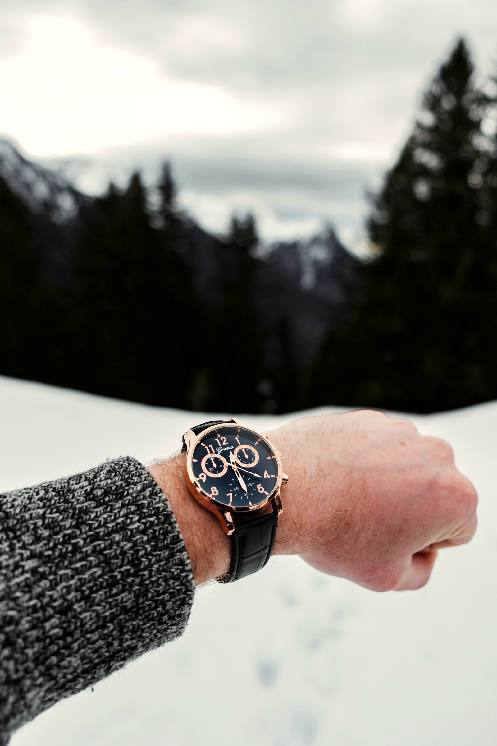 Chronograph watch on a wrist in the snow, worn with a knit cuff