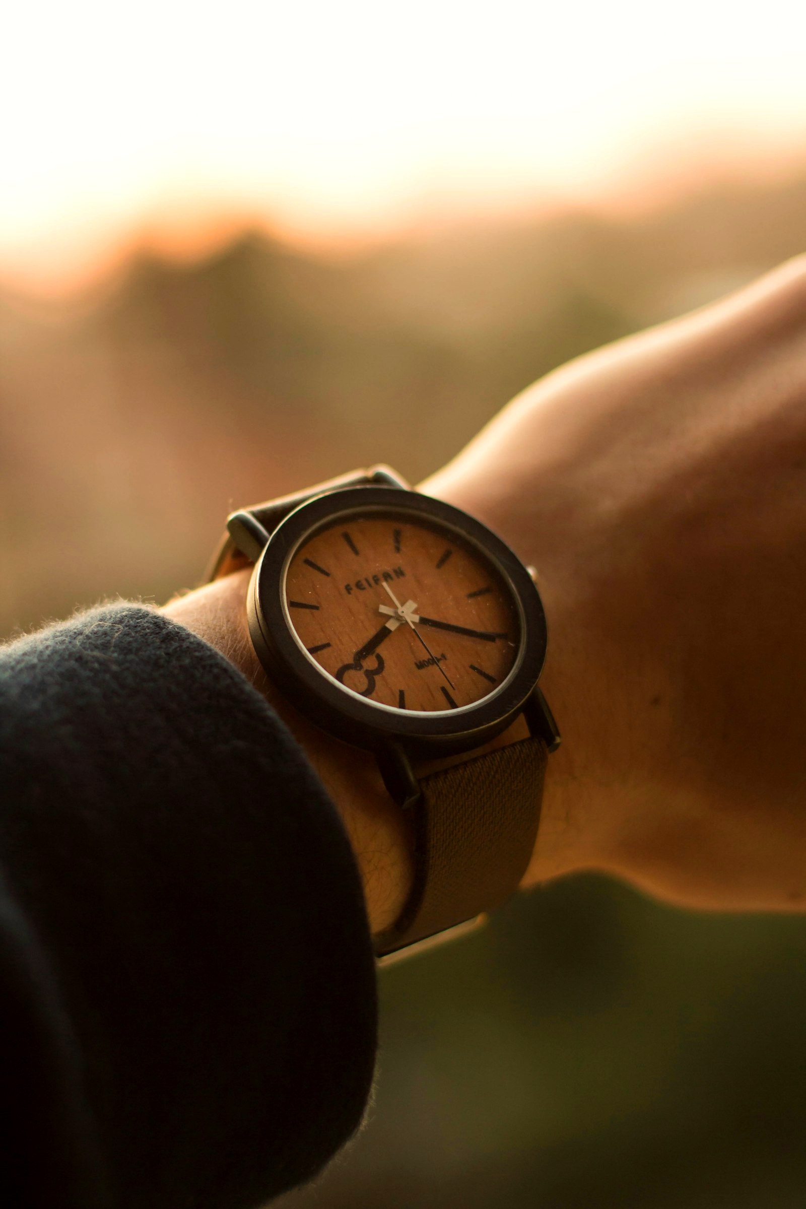 Minimal fashion watch with a plain dial on a leather strap, worn at sunset
