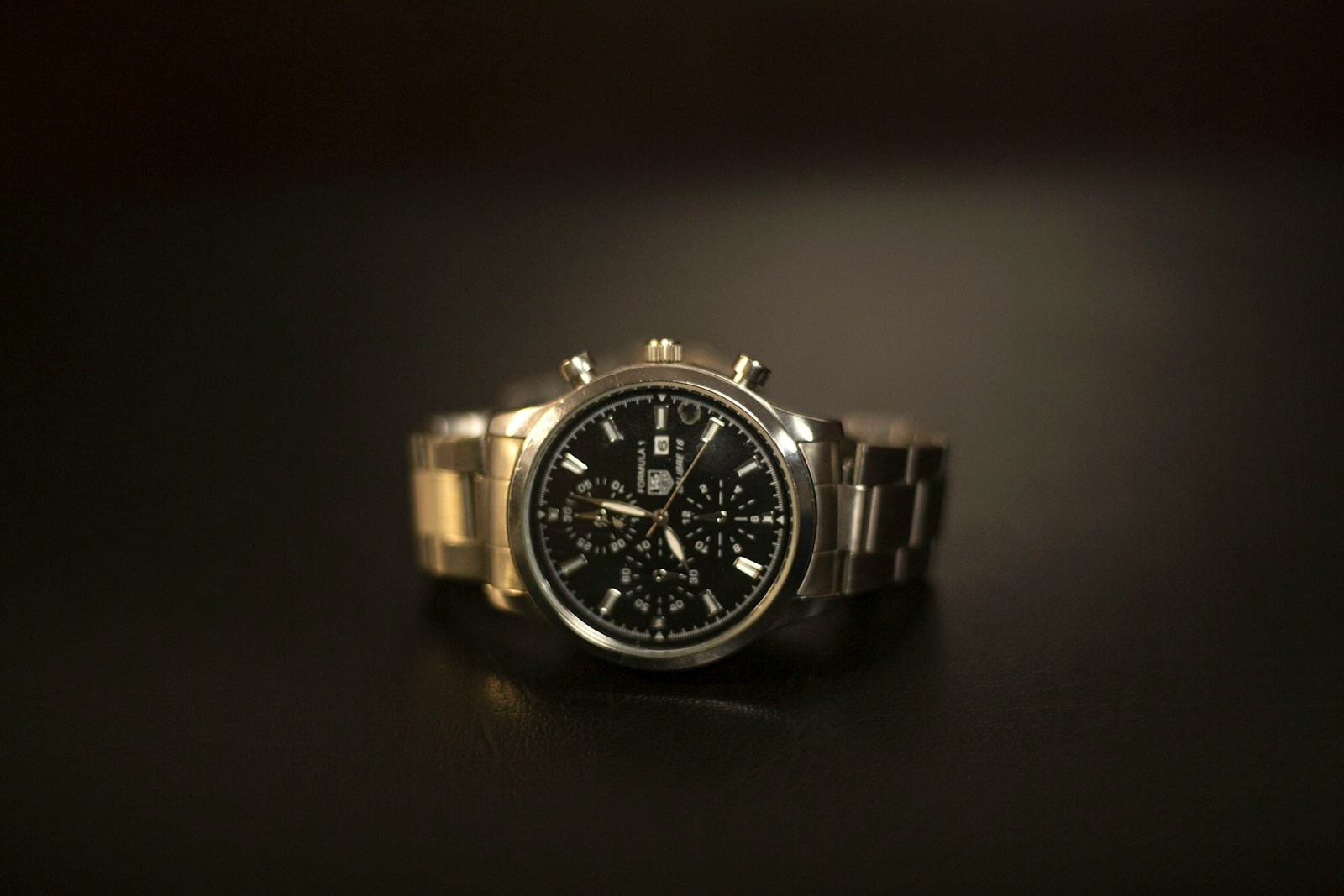 Steel bracelet watch resting on a dark surface in low light