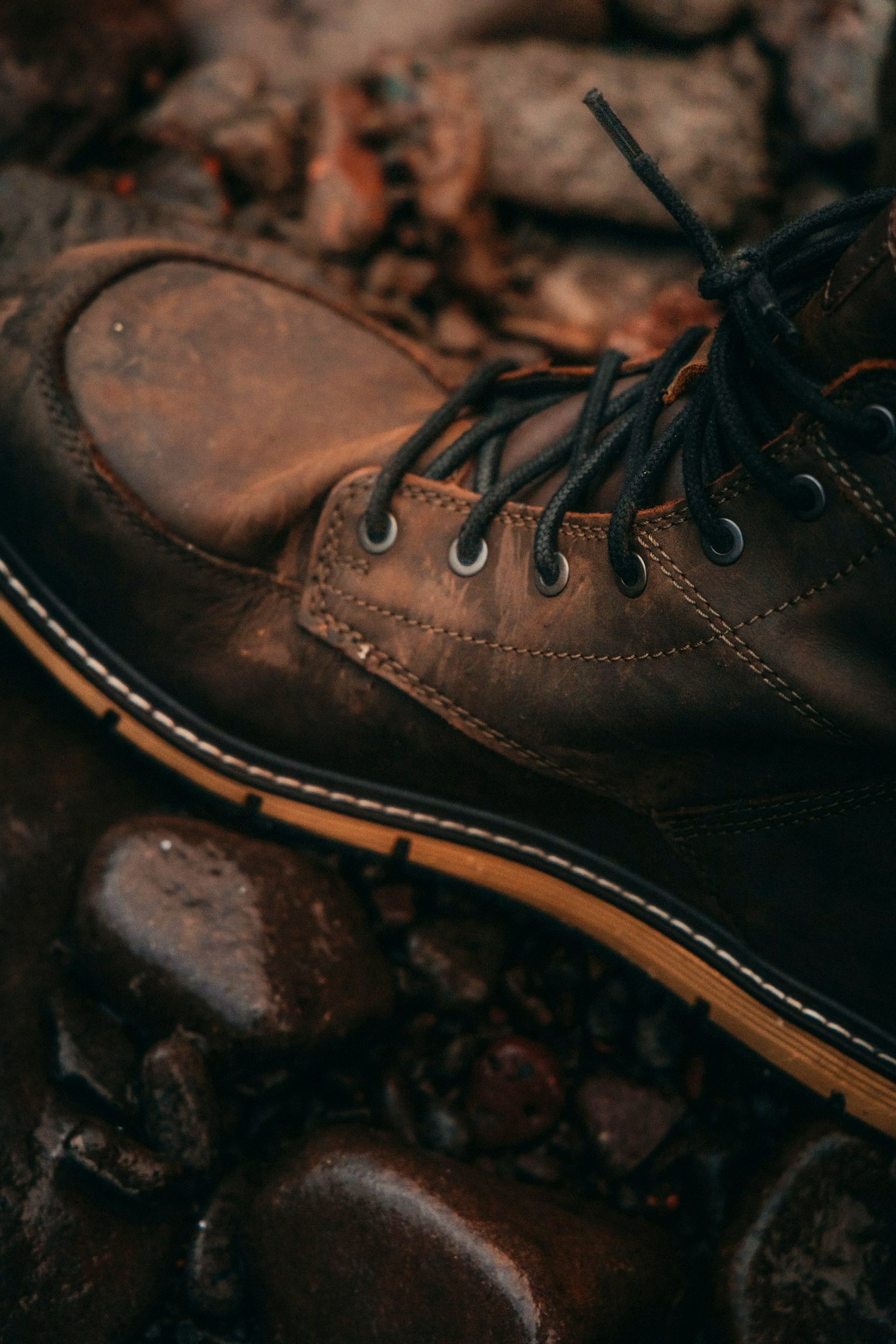 A worn brown leather boot on wet rocks, close-up