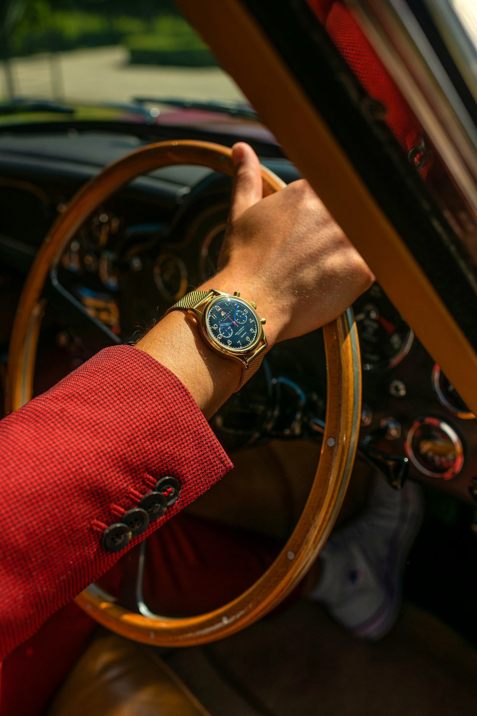 A wristwatch at the wheel of a vintage car, the driving light the aviator was built for