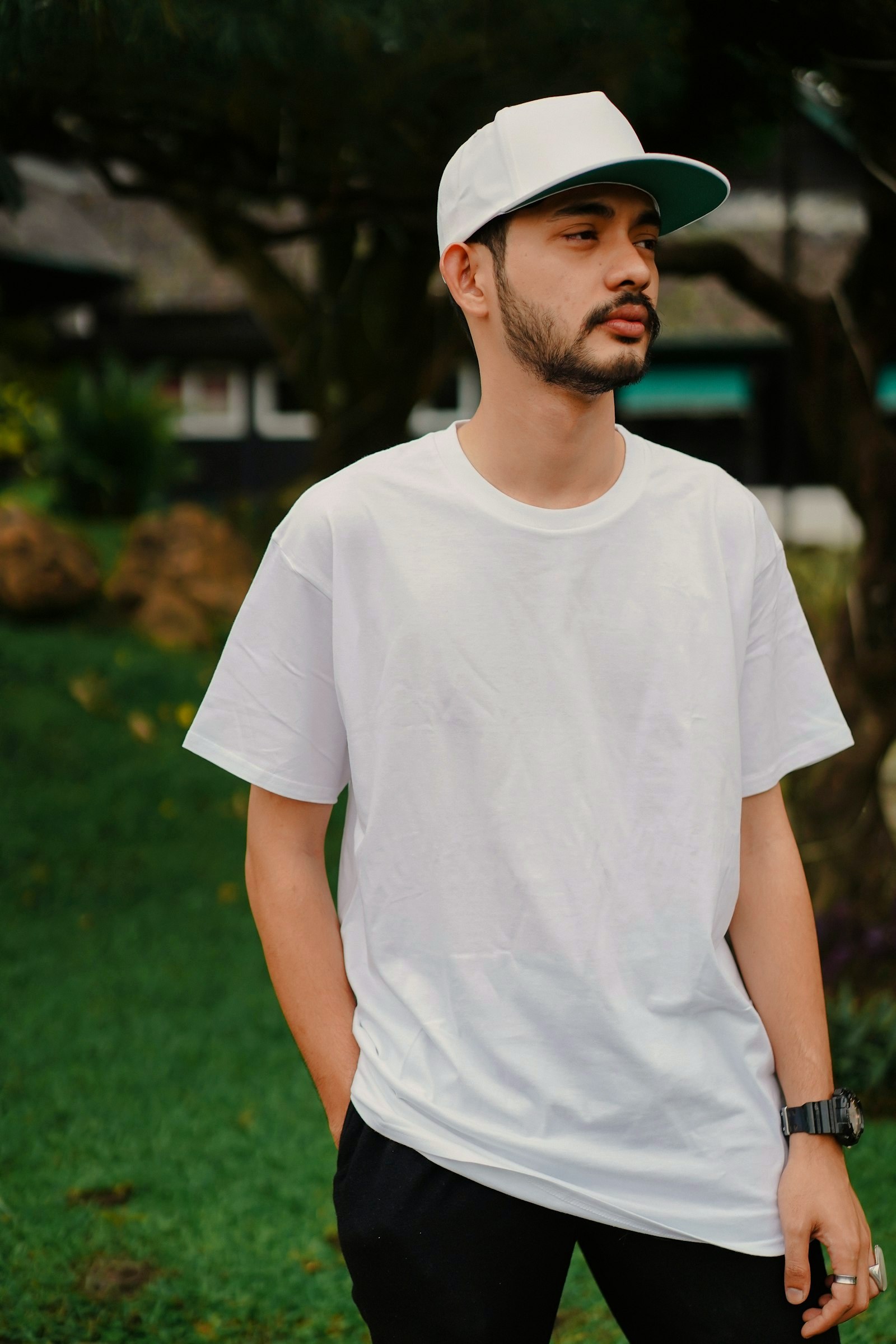 Young man wearing a boxy plain white t-shirt and white cap outdoors